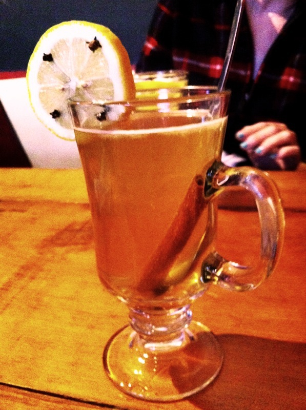 a glass of lemon tea with a slice of lemon sitting on the rim