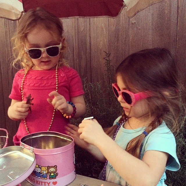 two little girls with sun glasses and beads making candy