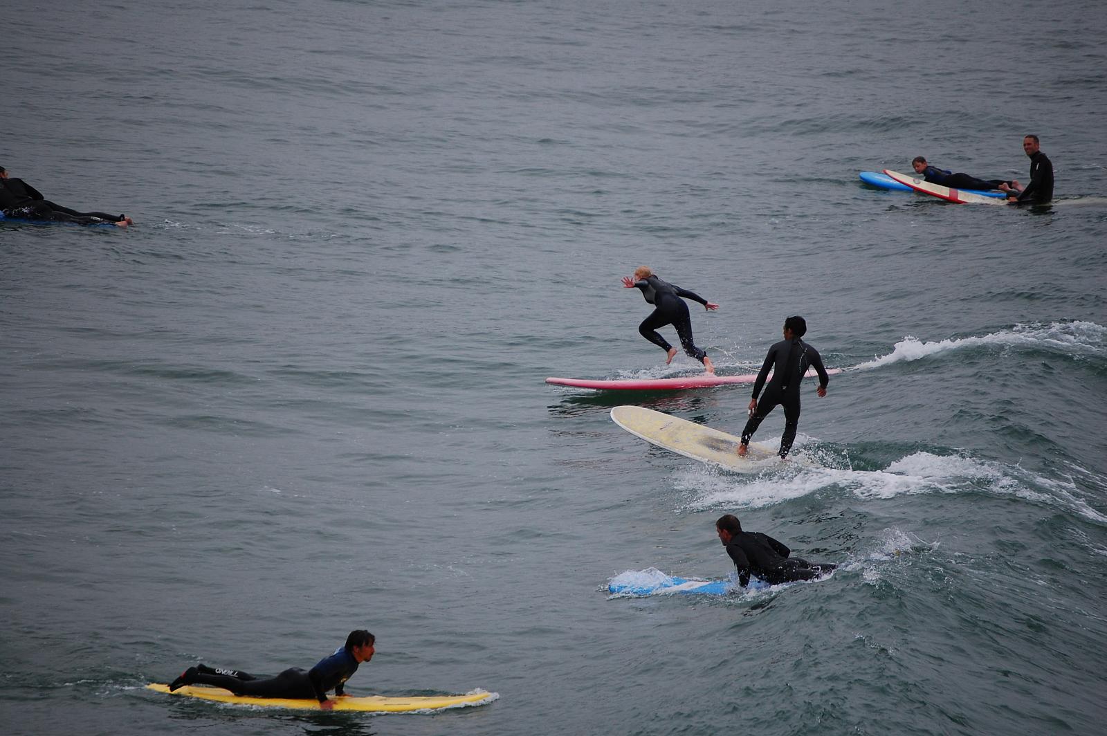 group of men standing on surfboards riding the same wave