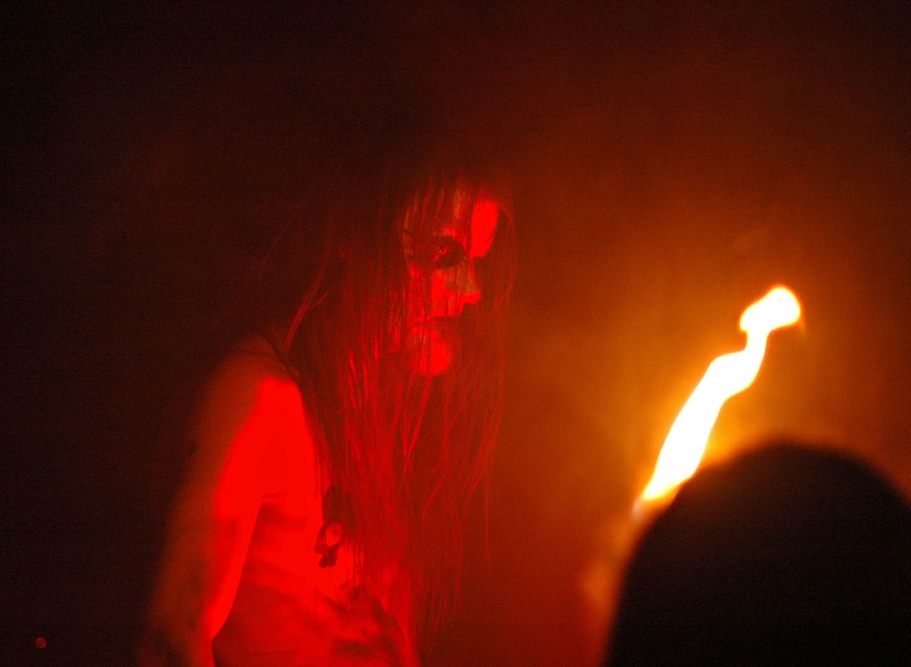 a young lady stands on stage with her hand out to light the candle