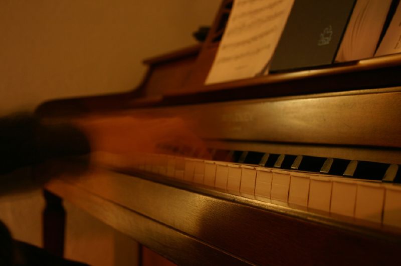 blurred piano and keyboard with musical notes and sheet music