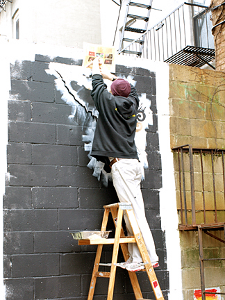 a man painting a black wall with white paints