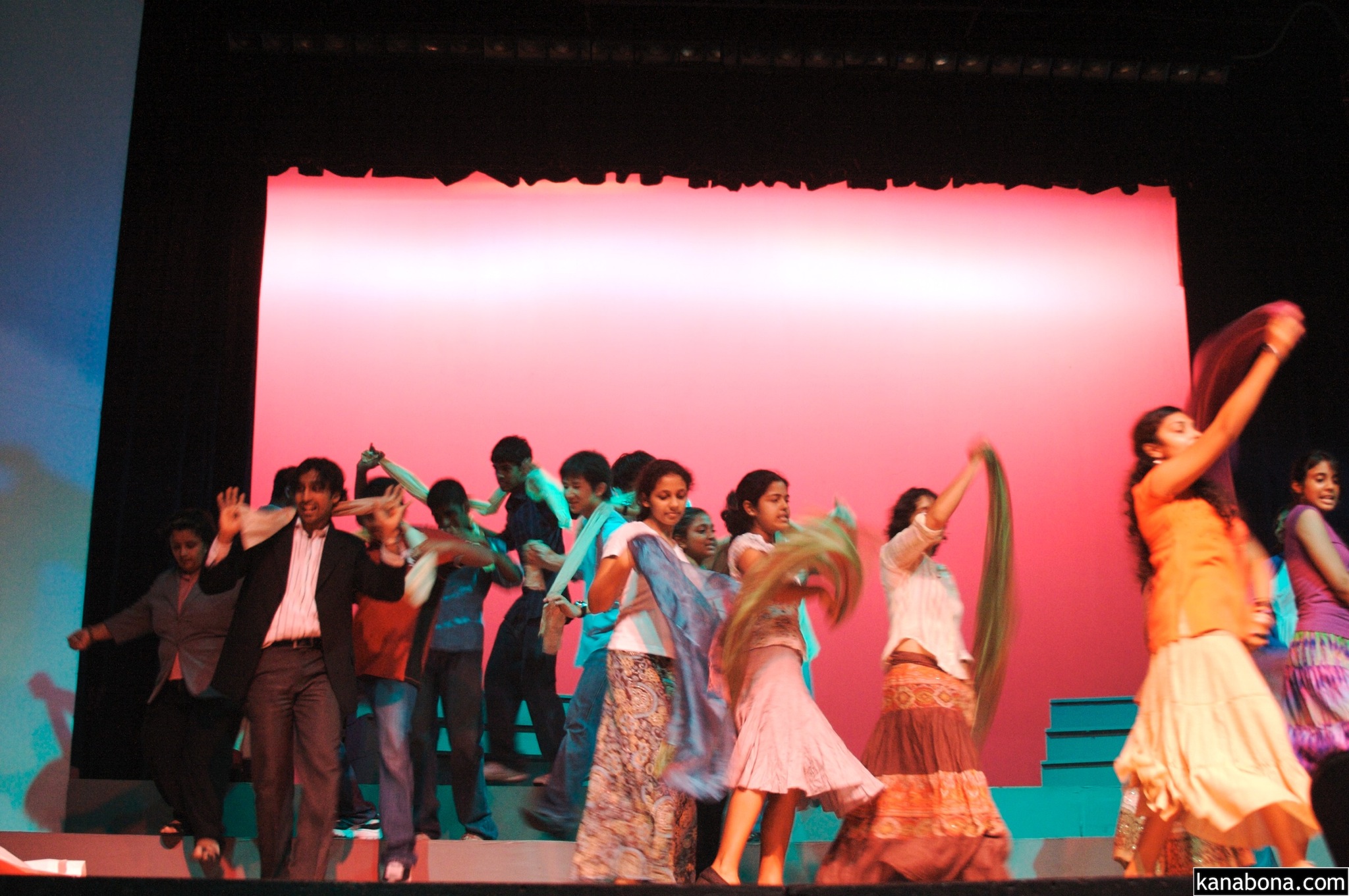 dancers dancing with arms raised in front of a big red wall