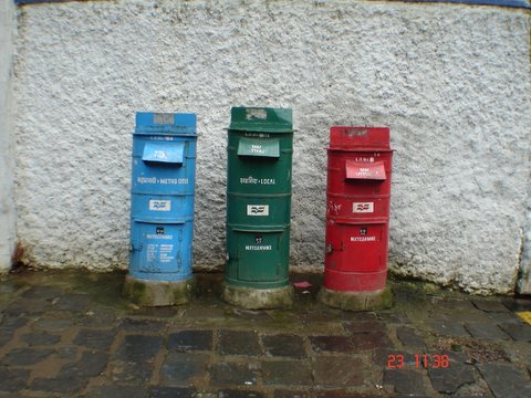 several empty red blue and green boxes lined up against a white wall