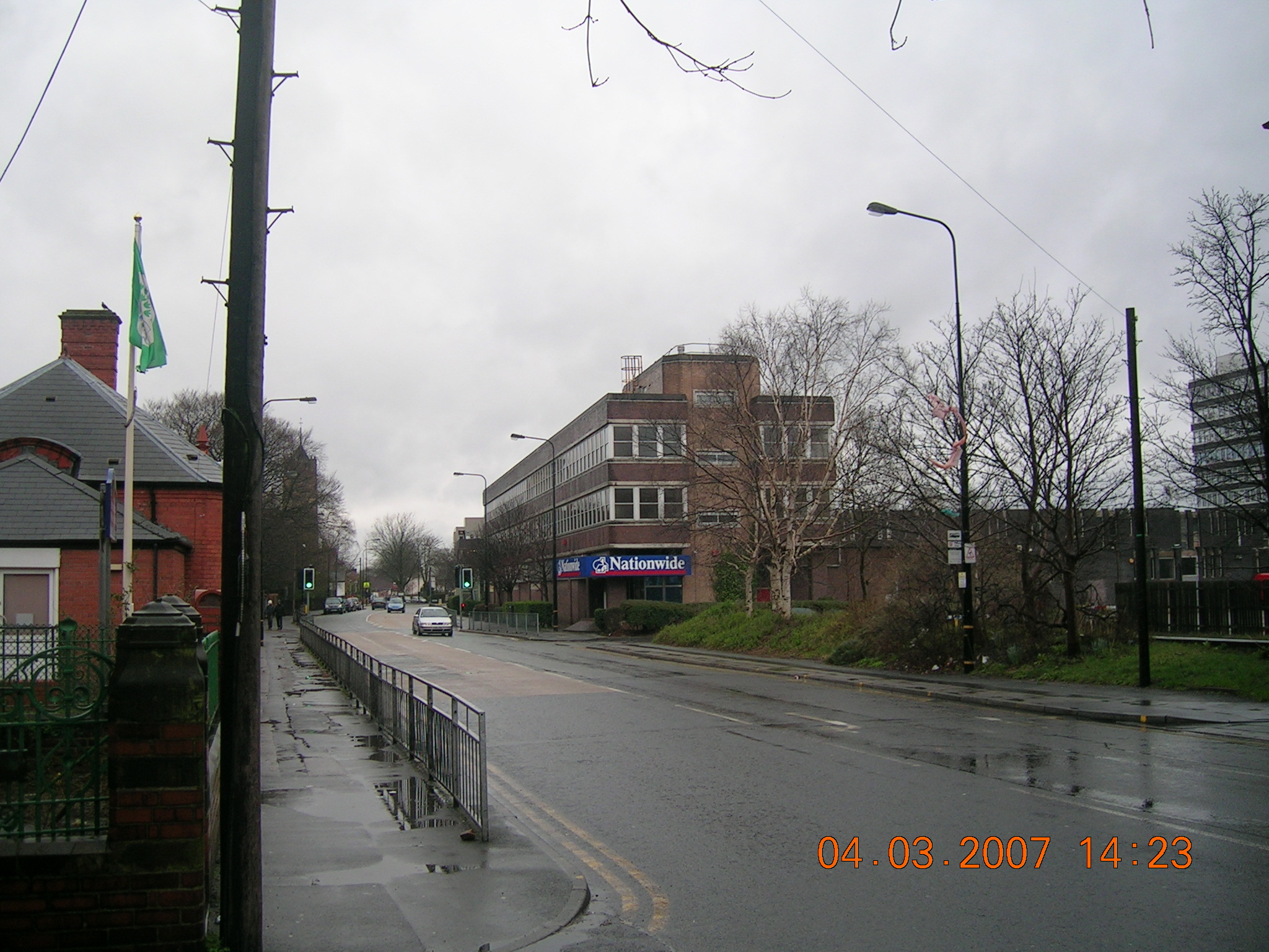 the intersection of a street with a building on one side and cars in the background