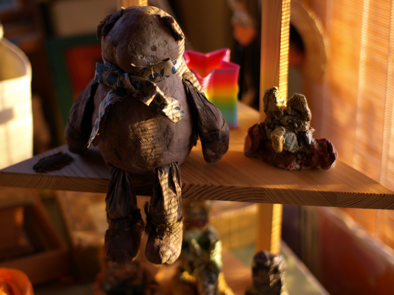 three tiny brown teddy bears sitting on wooden shelves