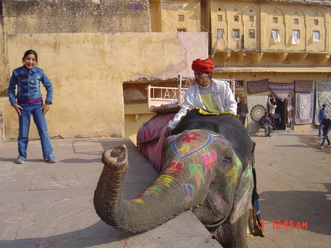 two people riding an elephant with a paint covered trunk