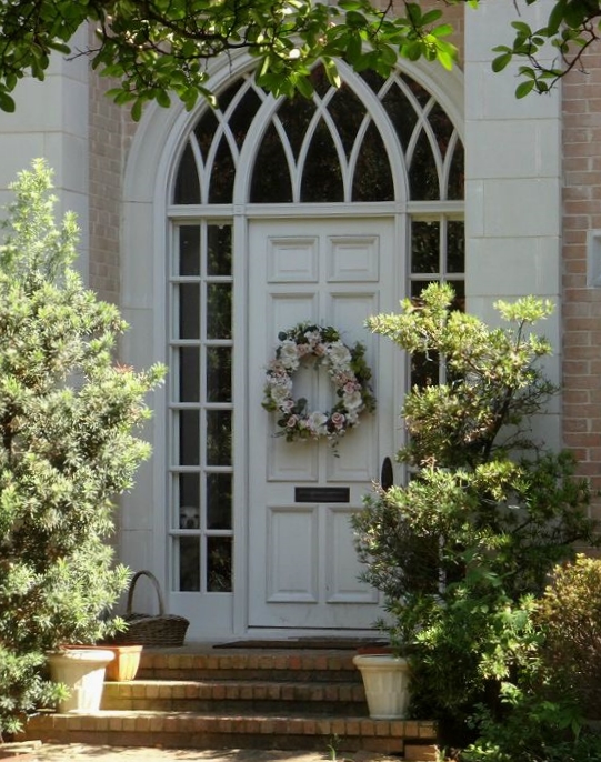 a door with wreath on it stands on a porch in front of a brick building