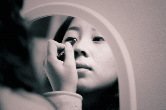 an asian girl examines her reflection in a mirror