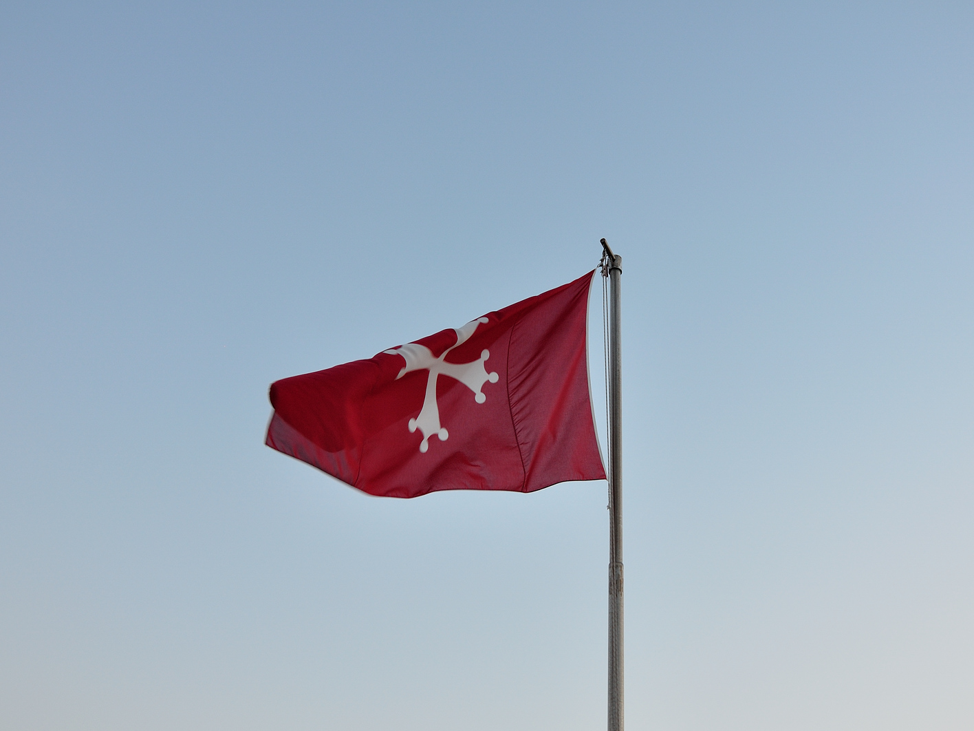 a flag waving on the top of a tall pole