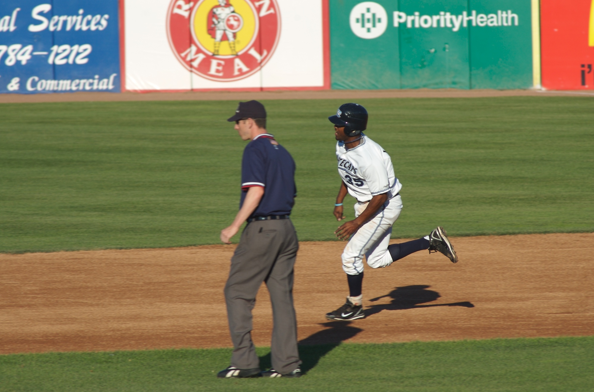 a baseball player running toward the mound near another person