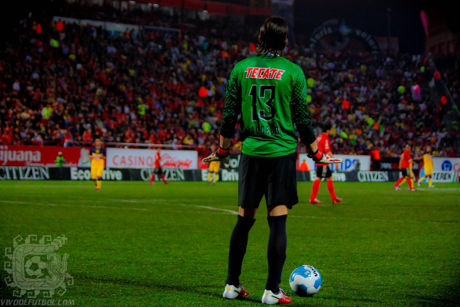 the soccer player in a green uniform stands next to his ball