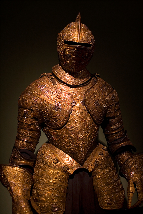 a metallic armor is displayed on the black backdrop