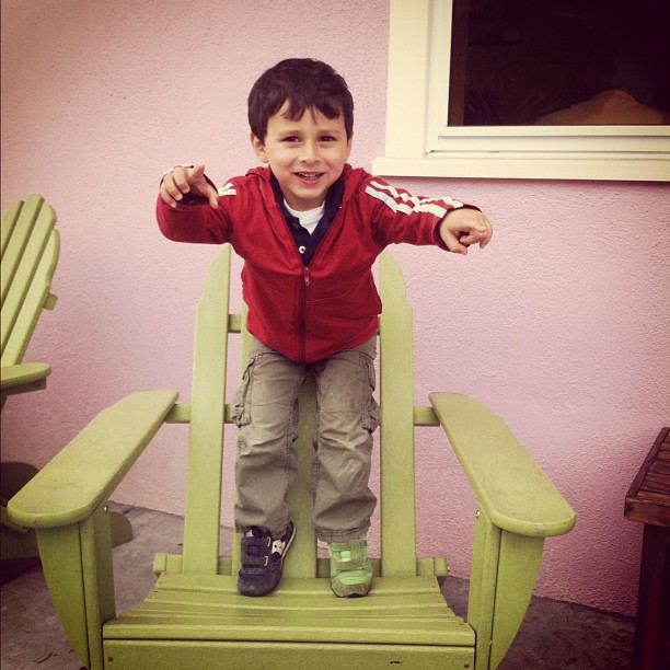 a boy posing on top of an adi - pops chair
