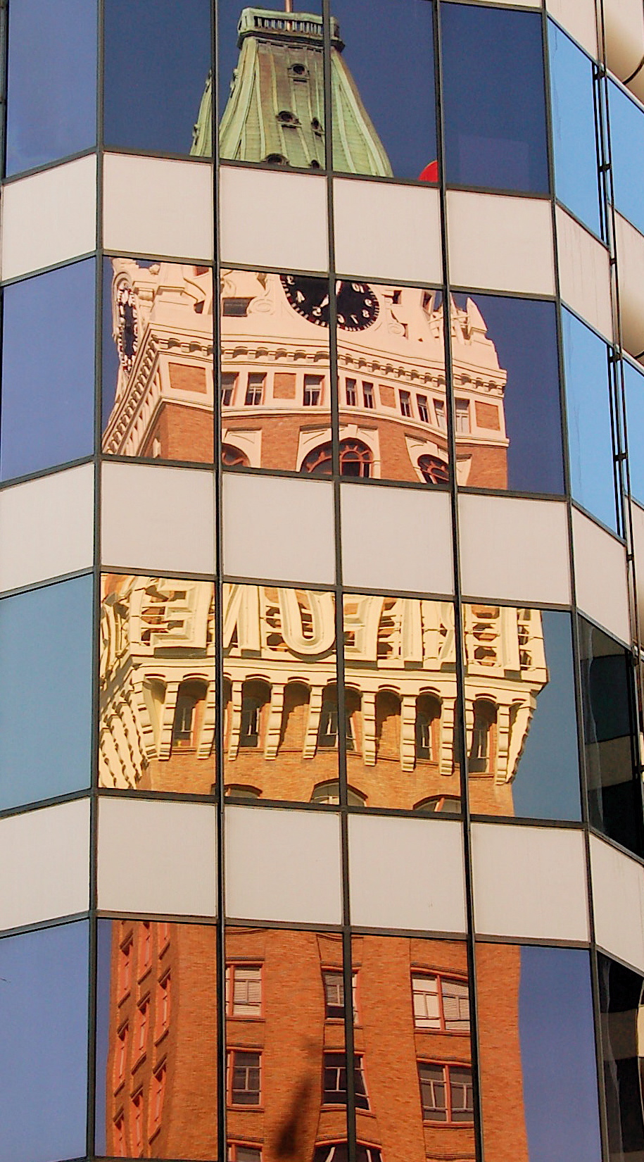 a very large building and clock tower reflected in some buildings windows