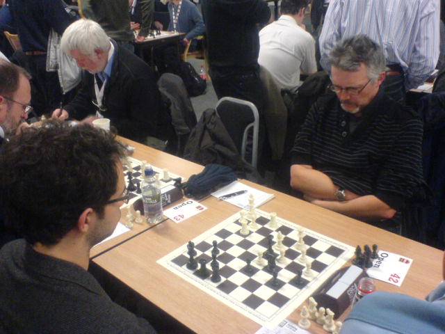 chess players are sitting at a table with their boards