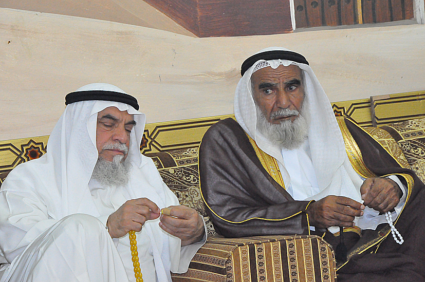 three men sitting together while using electronic devices