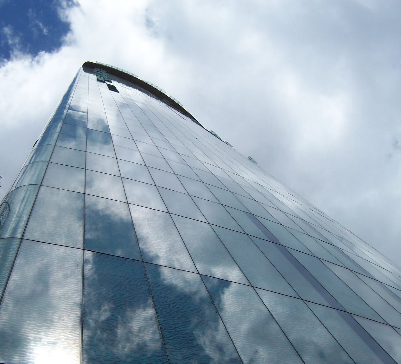 an upward view of a building with blue sky and clouds