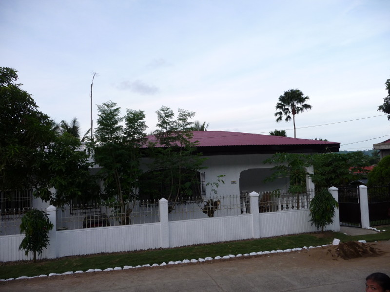 an old white home that is white and has a pink roof