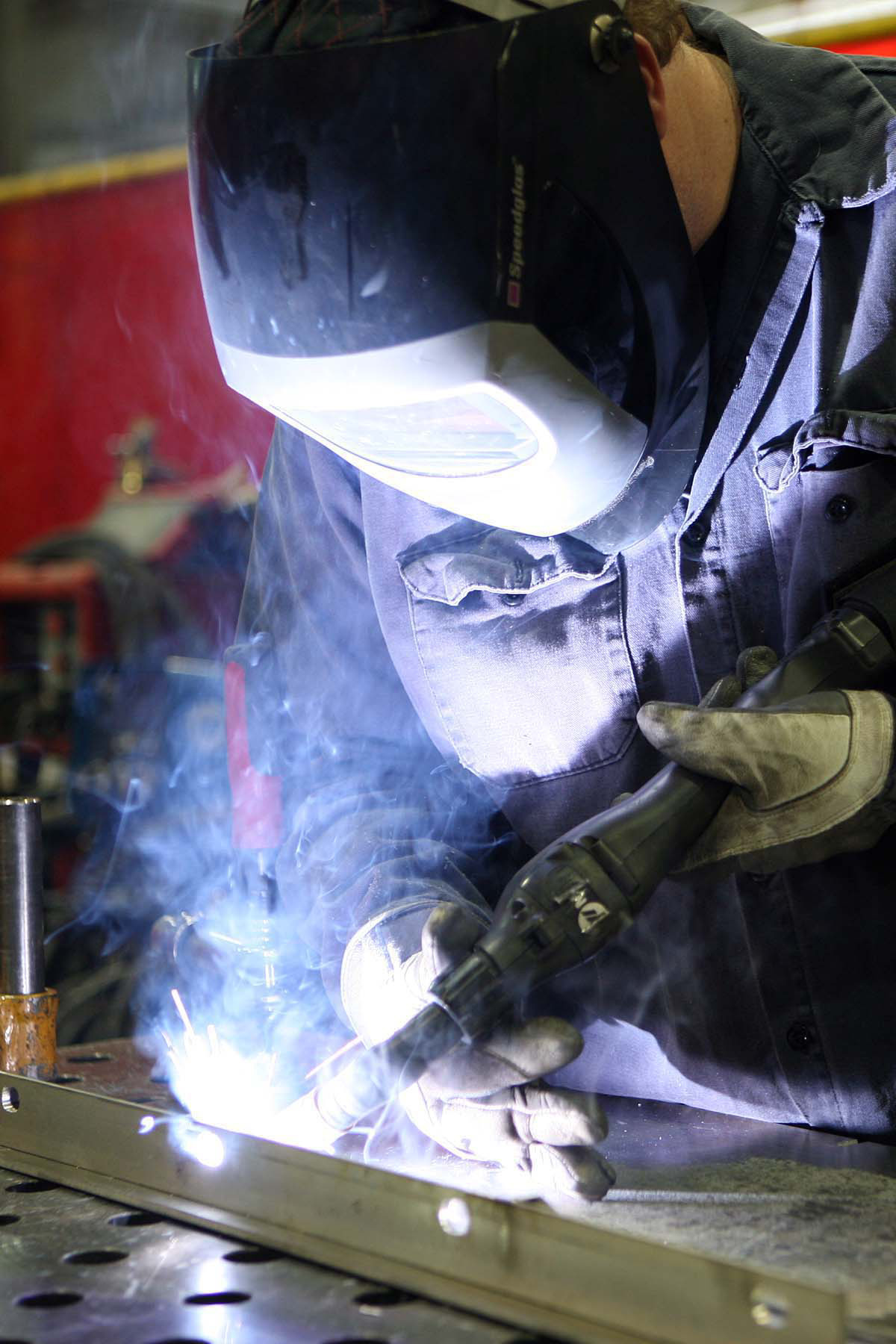 an automotive worker is grinding metal with a grinder