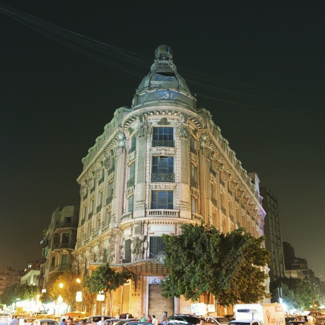 a building lit up at night in the middle of an intersection