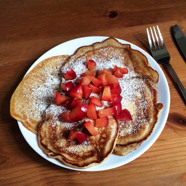 a white plate topped with three pancakes covered in powdered sugar and garnish