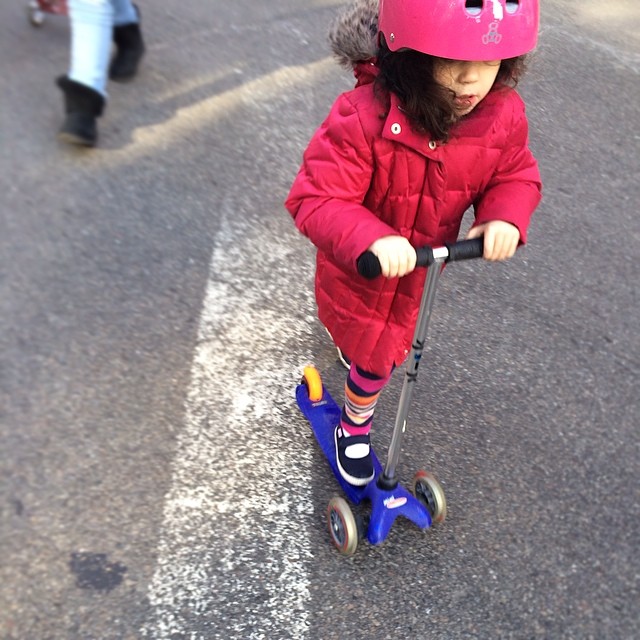 a child is wearing a pink helmet and riding a scooter