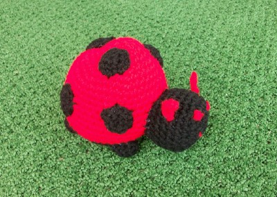 a crocheted red and black bug with two small bugs attached
