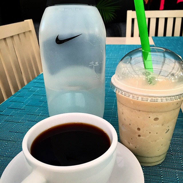 a cup of coffee with a straw next to a glass container
