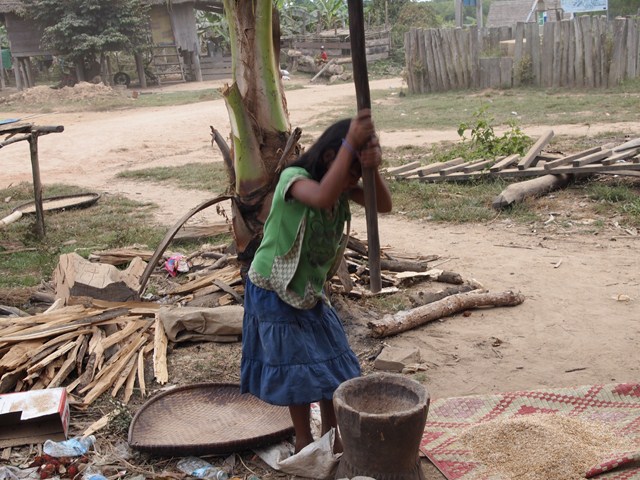 a child is holding a pole by a basket in front of a makeshift shed