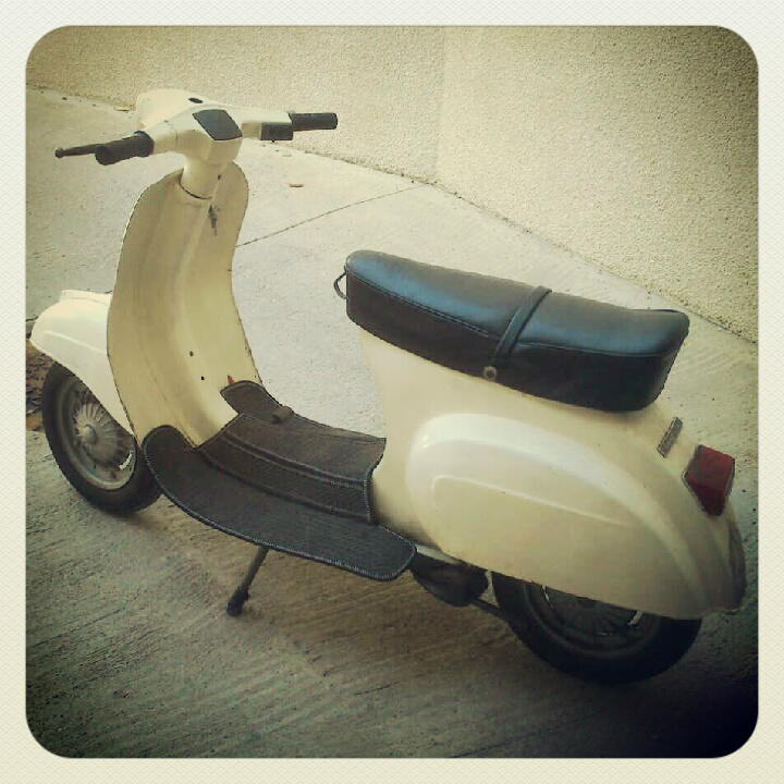 this is a vintage moped parked on the side walk