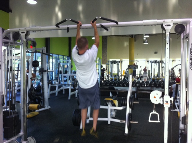 a man performs chin - lifts on a pull up bar in the gym