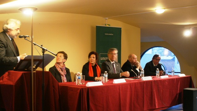 several people at a table in a hall with microphones and chairs