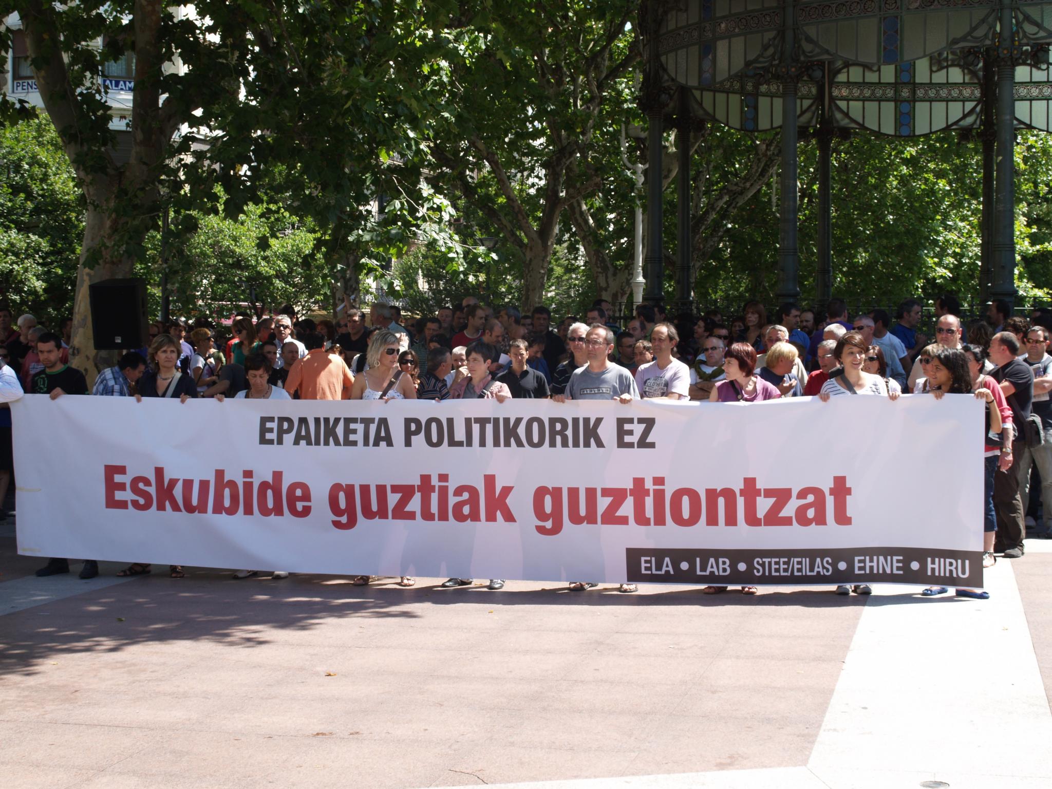 a man stands in front of an event while people hold up a white banner