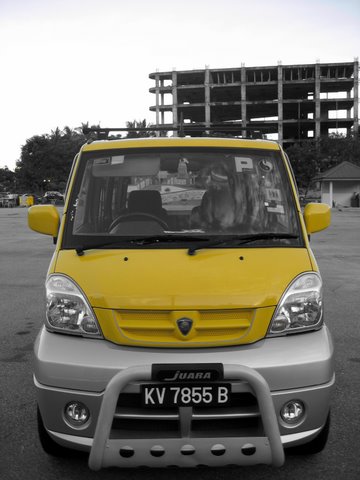 yellow car parked in parking lot with cars nearby