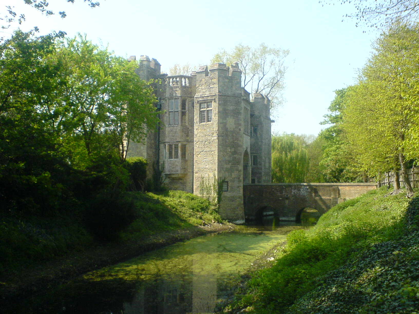 a castle perched on top of a grassy hill next to a river