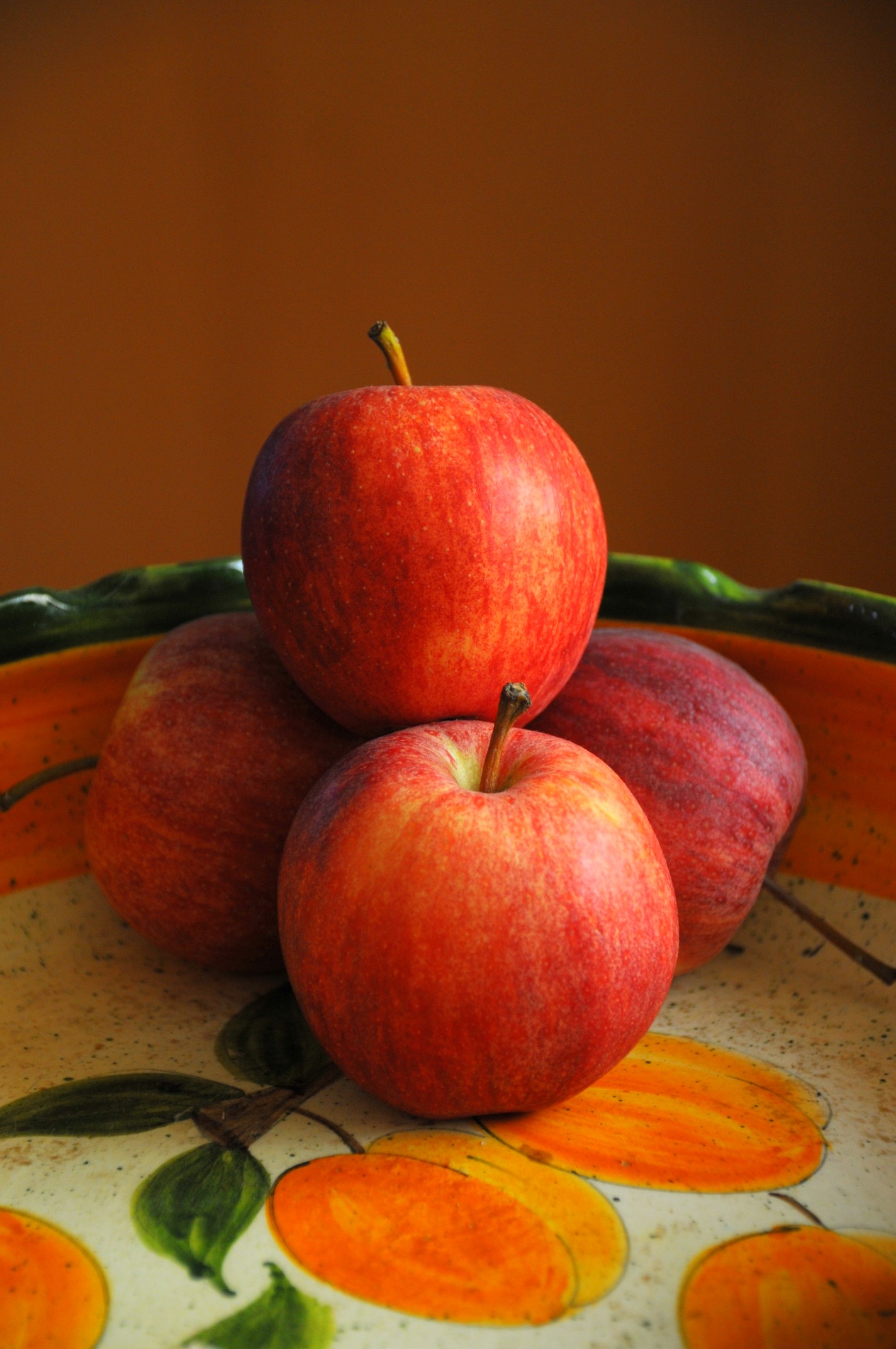 four apples are sitting on top of a flowered bowl