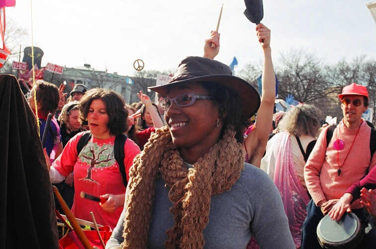 a woman with a large hat and scarf at a crowd