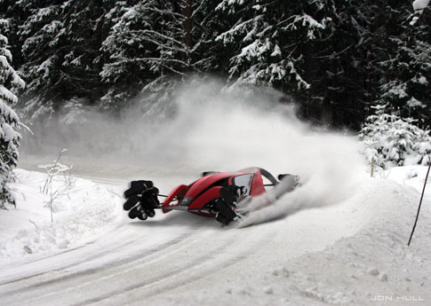 a red snow mobile in the snow being pulled by the back of a truck