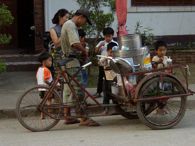a bicycle with a cart attached to it has many children