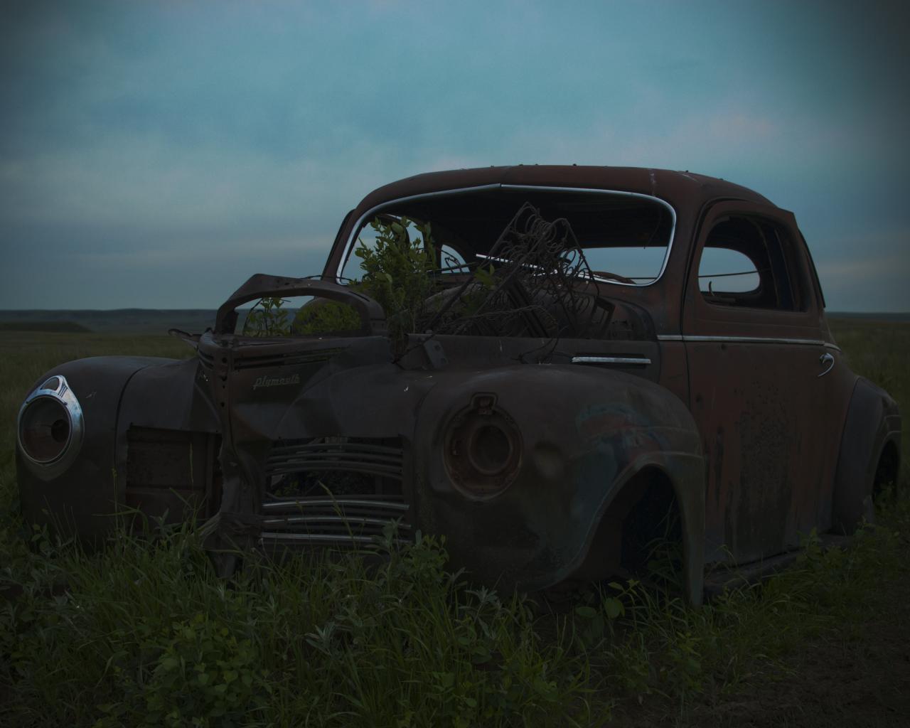 an old truck in a grassy field with the back door open