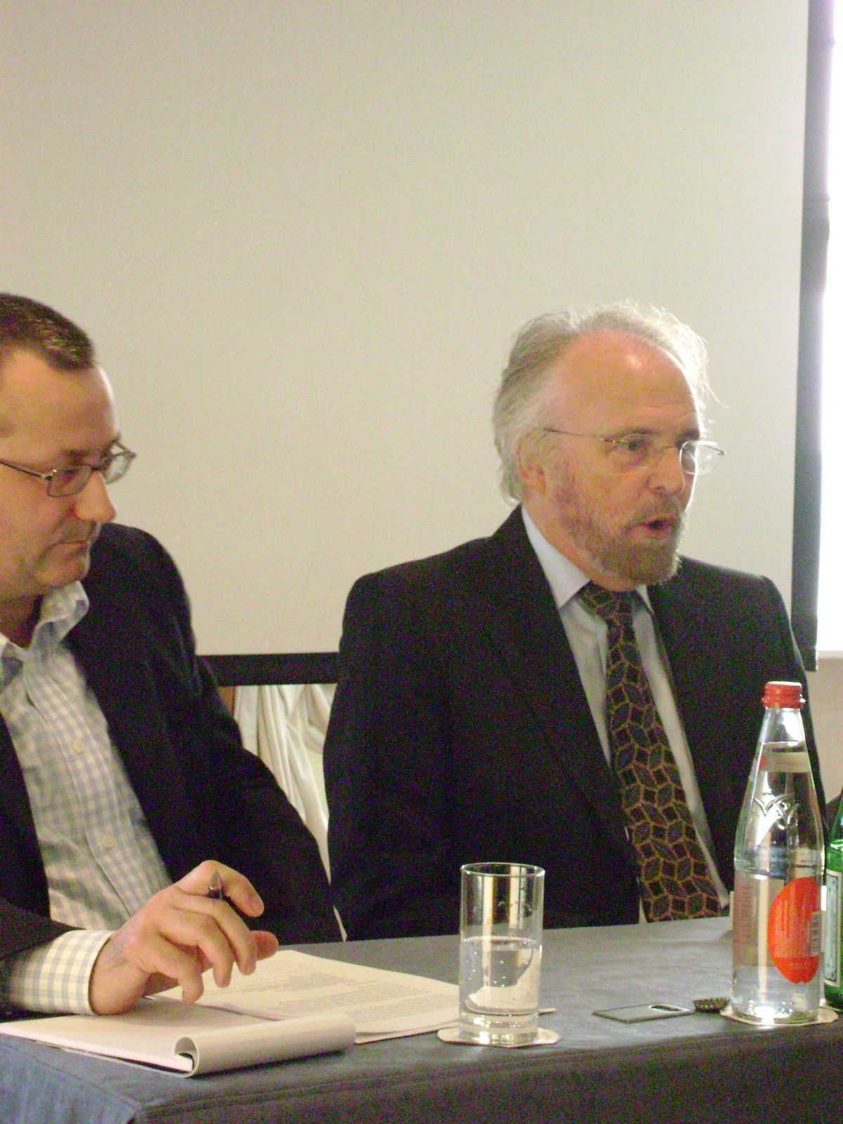 two men in business attire are sitting at a table