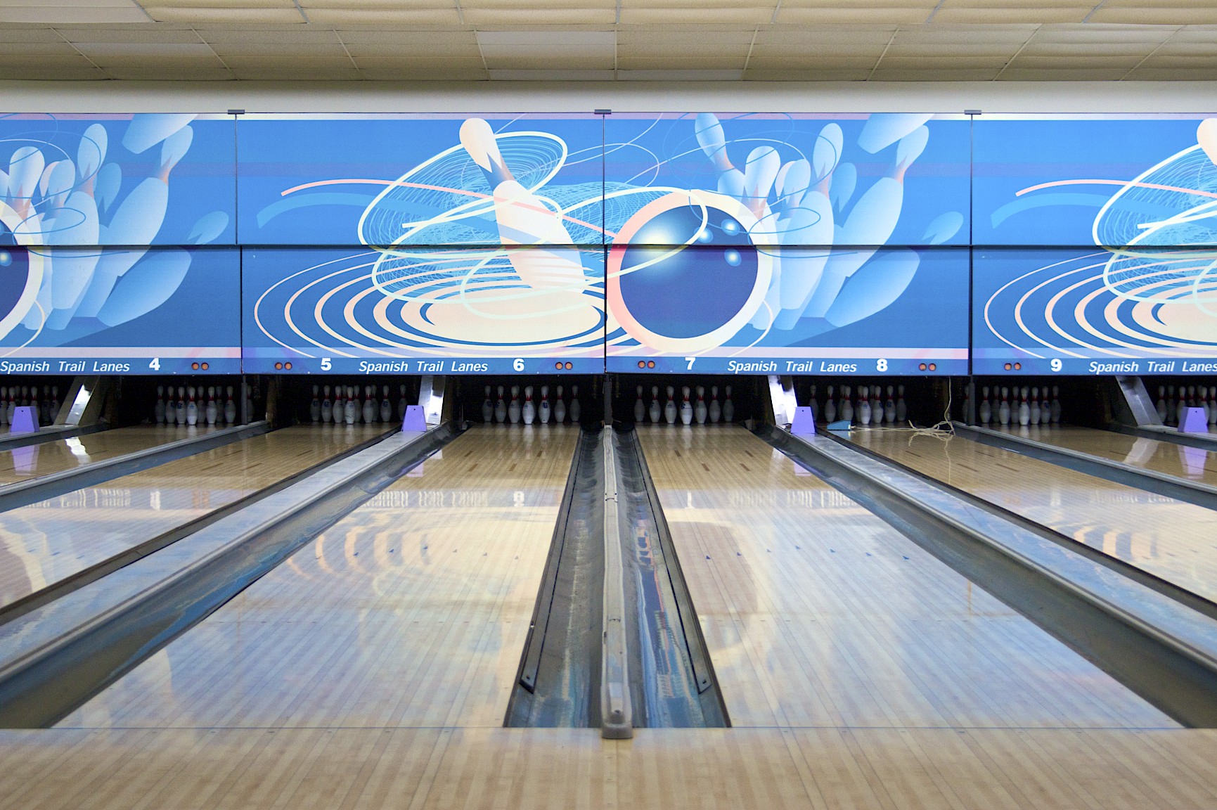 bowling alley with signs behind the lanes in front of it