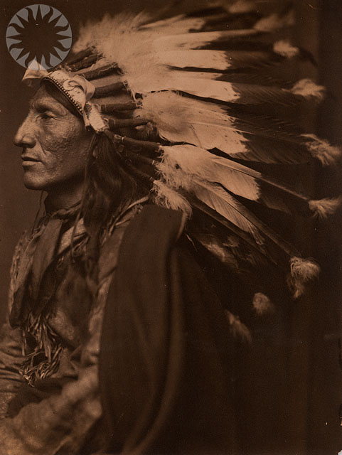 an old pograph of an indian man wearing a headdress