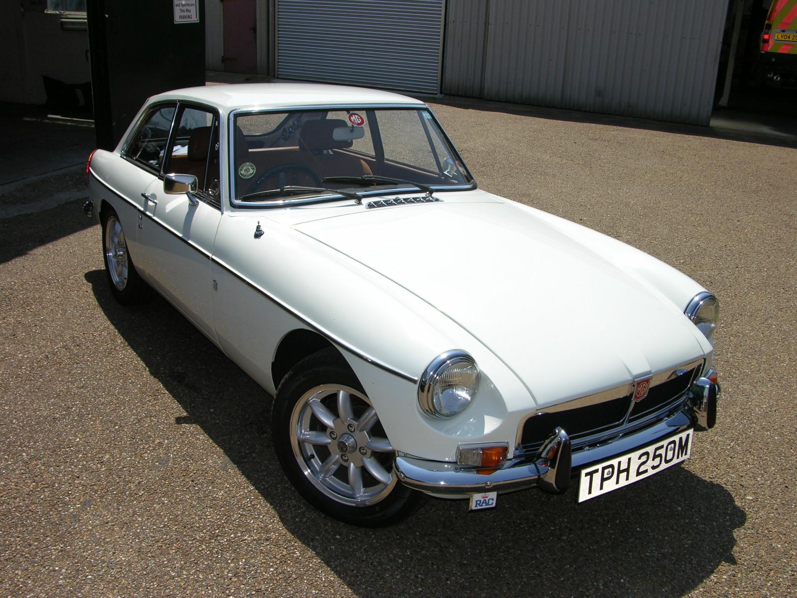 a white classic sports car with a license plate on the side