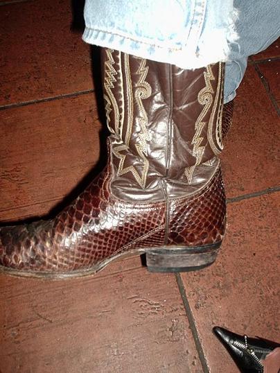 a woman's brown cowboy boots sitting on top of a brick floor