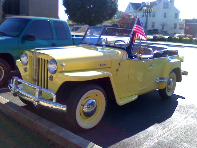 a yellow jeep with an american flag in the back