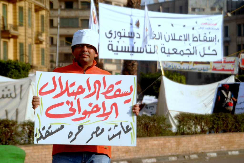 a protester holding up a sign and protesting in front of some buildings