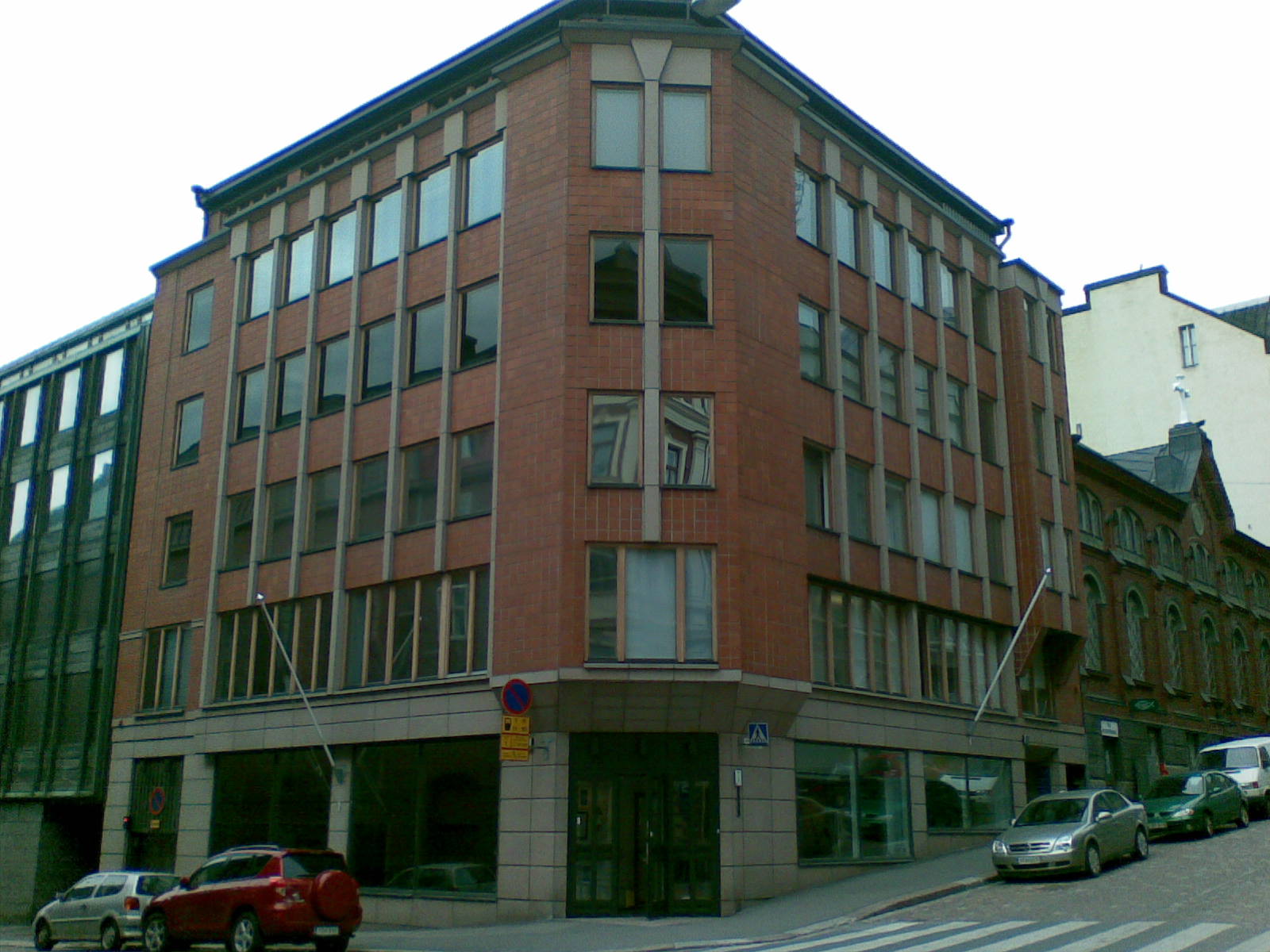 a brick building with two levels, some cars are on the street