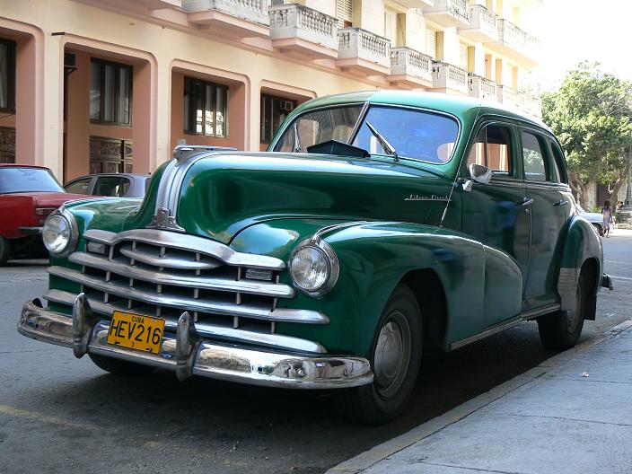 an old, green car parked on the side of a street